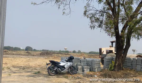 Panoramic view of the Prestige Golden Grove project site in Velimela, Hyderabad, showing initial ground leveling, boundary fencing, and early infrastructure development for the upcoming 10-tower luxury high-rise township.